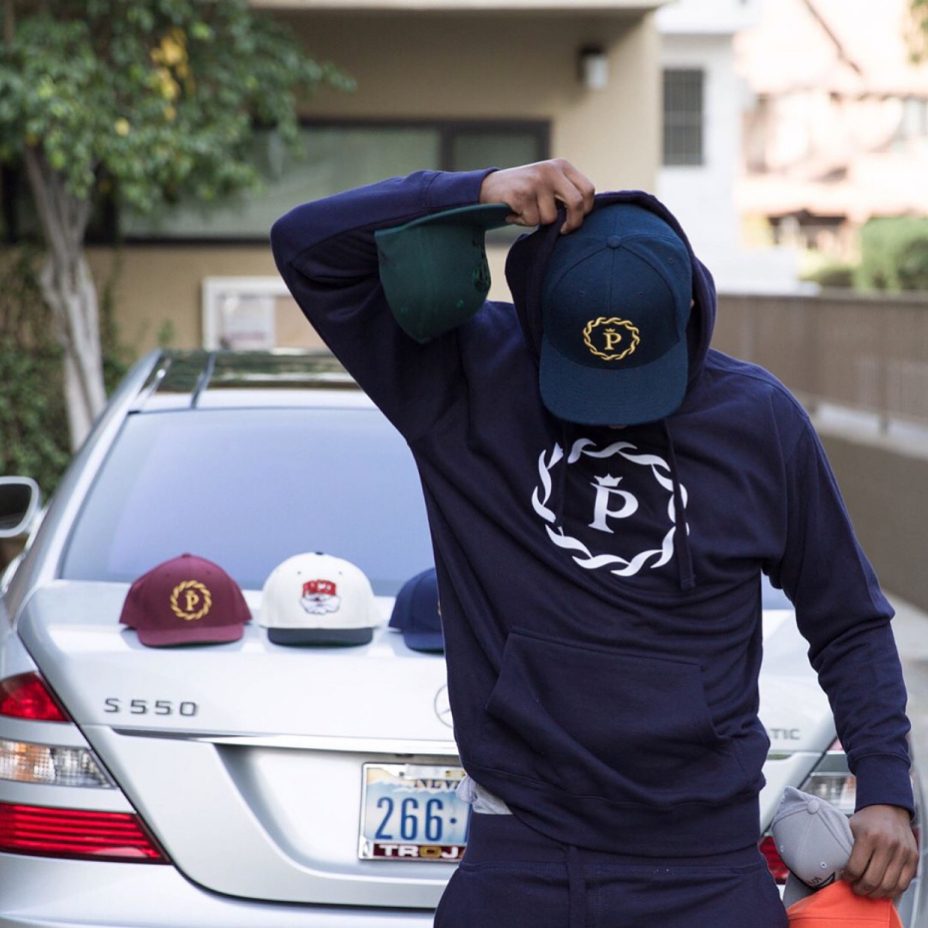 Armand Perry (CBA Peez) in PRCZN Sweatshirt + Hat, phone call outside Twin Palms Apartments